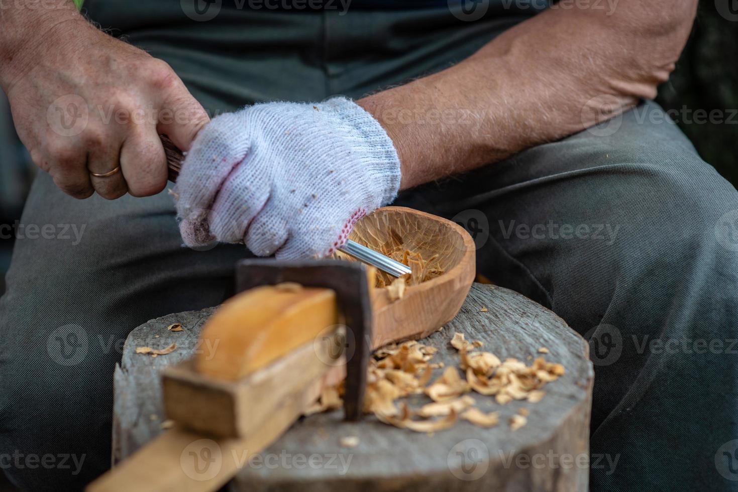 Handwerker zeigt den Prozess der Herstellung von Holzlöffeln foto