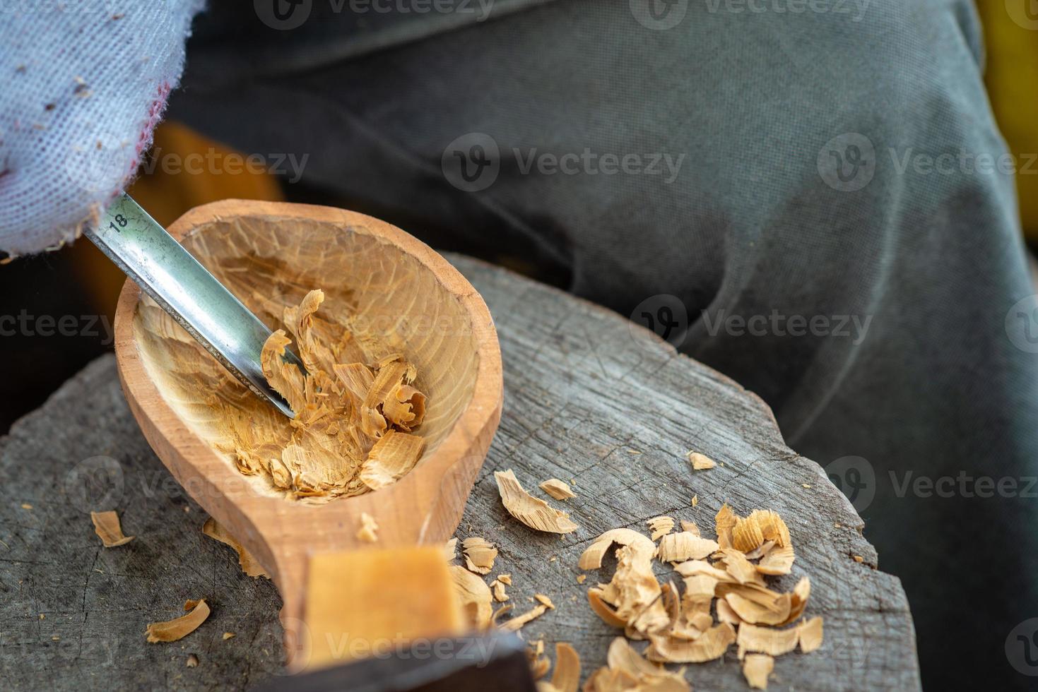 Handwerker zeigt den Prozess der Herstellung von Holzlöffeln foto