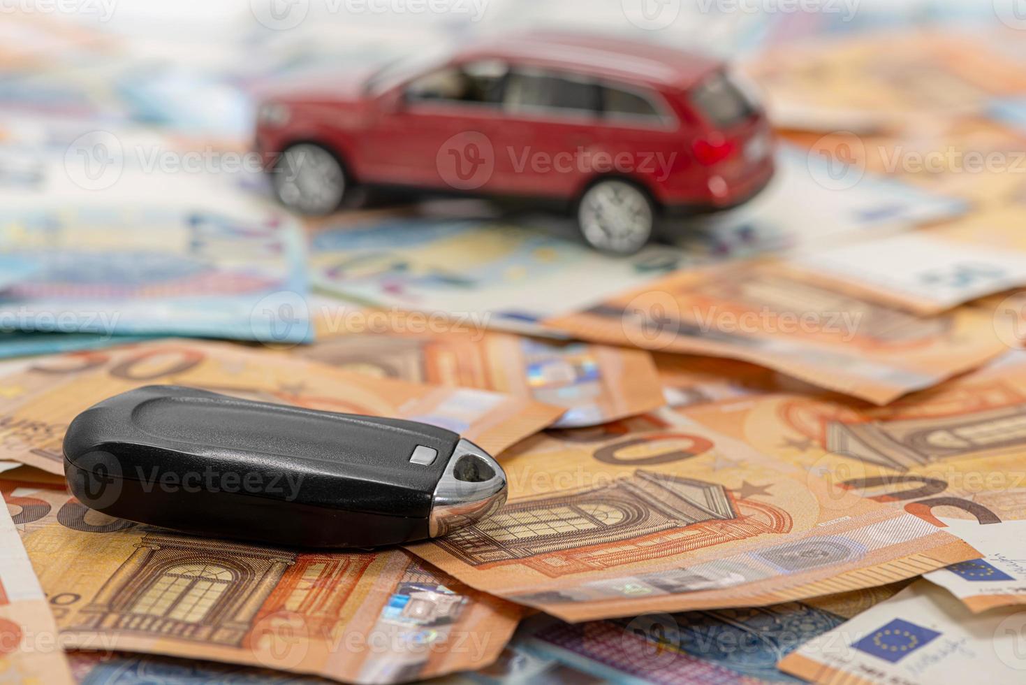 Schlüssel und rotes Spielzeugauto auf Haufen von Euro-Banknoten foto