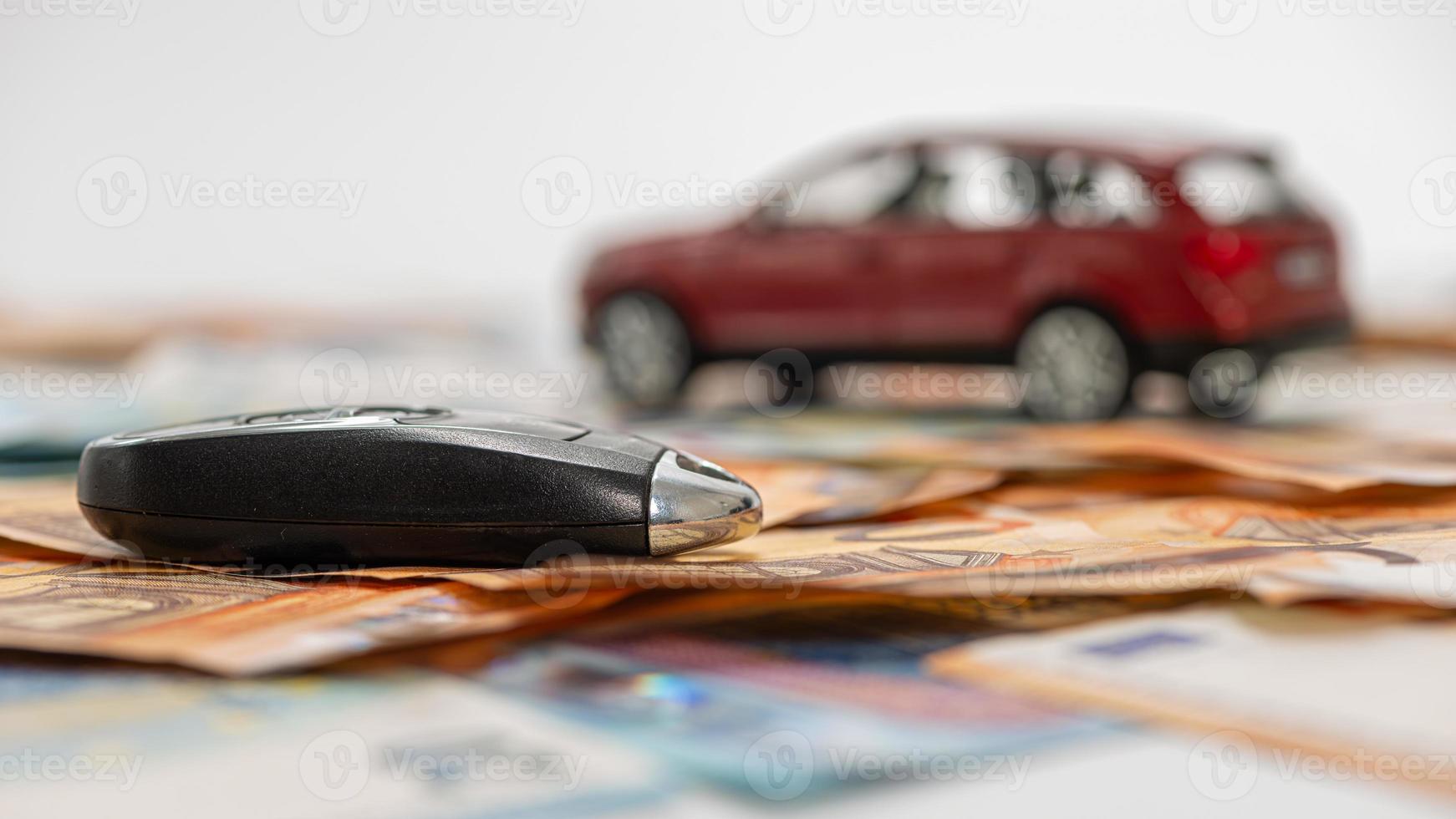 Schlüssel und rotes Spielzeugauto auf Haufen von Euro-Banknoten foto