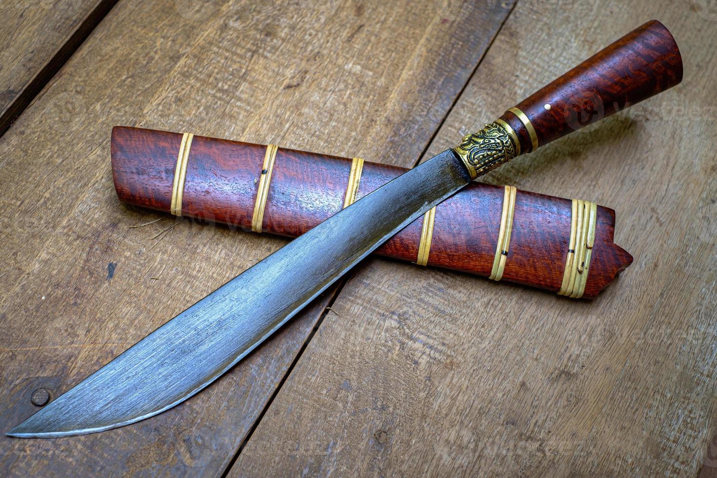 Messer benutzerdefinierte oder enep in der natürlichen holzscheide auf altem tischhintergrund handgefertigt aus thailand foto
