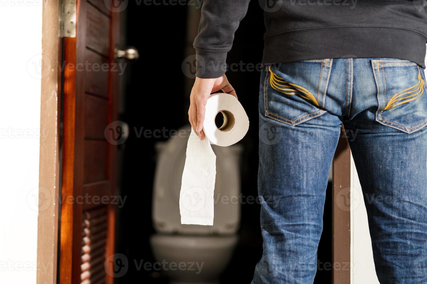 Mann hält Taschentuchrolle in Toilette foto
