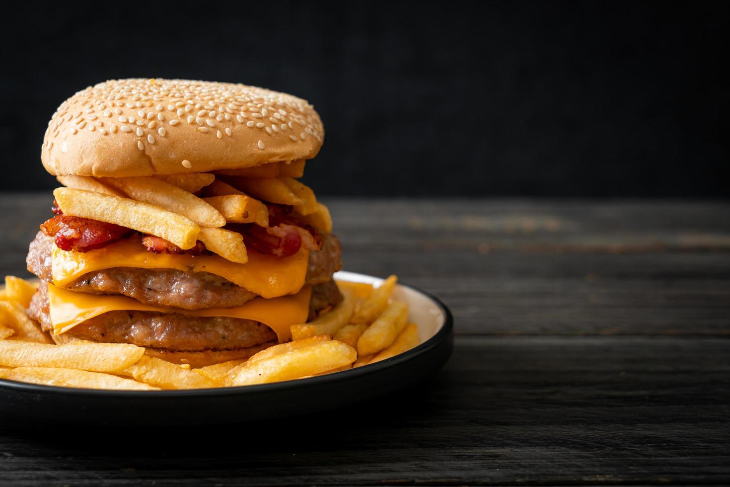 Schweinefleisch-Hamburger oder Schweinefleisch-Burger mit Käse, Speck und Pommes frites foto