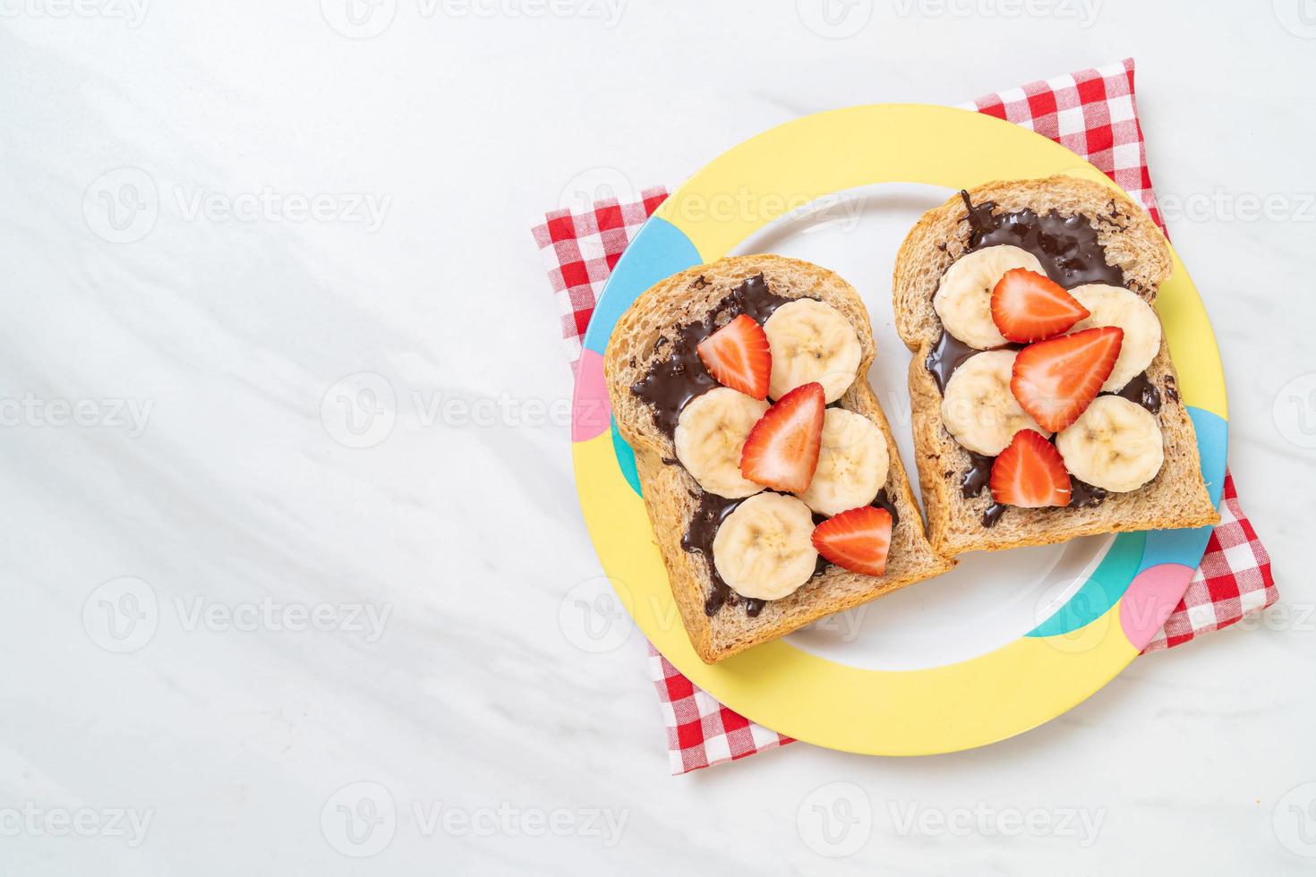 Vollkornbrot geröstet mit frischer Banane, Erdbeere und Schokolade zum Frühstück foto