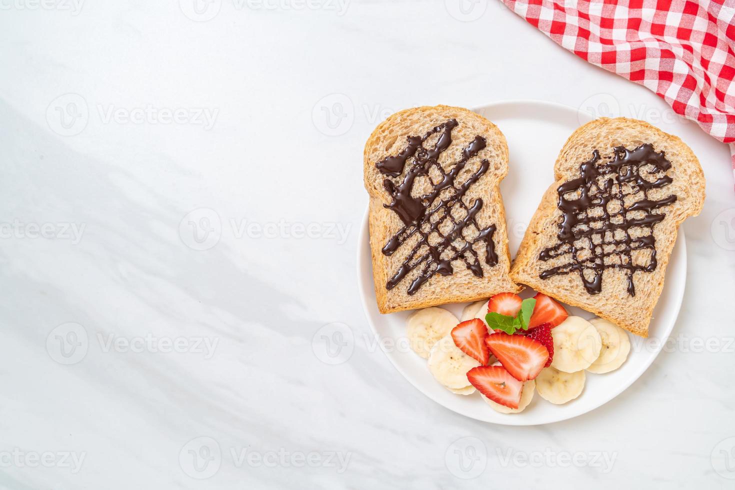 Vollkornbrot geröstet mit frischer Banane, Erdbeere und Schokolade zum Frühstück foto