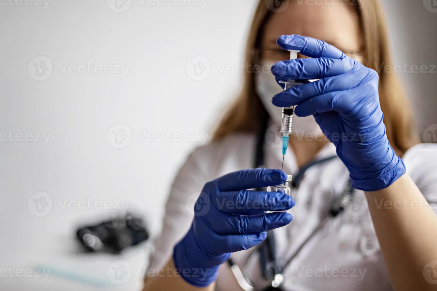 Eine Ärztin, die eine medizinische Maske trägt, zieht den Coronavirus-Impfstoff in der Klinik in eine Spritze. Das Konzept der Impfung, Immunisierung, Prävention gegen Covid-19. foto