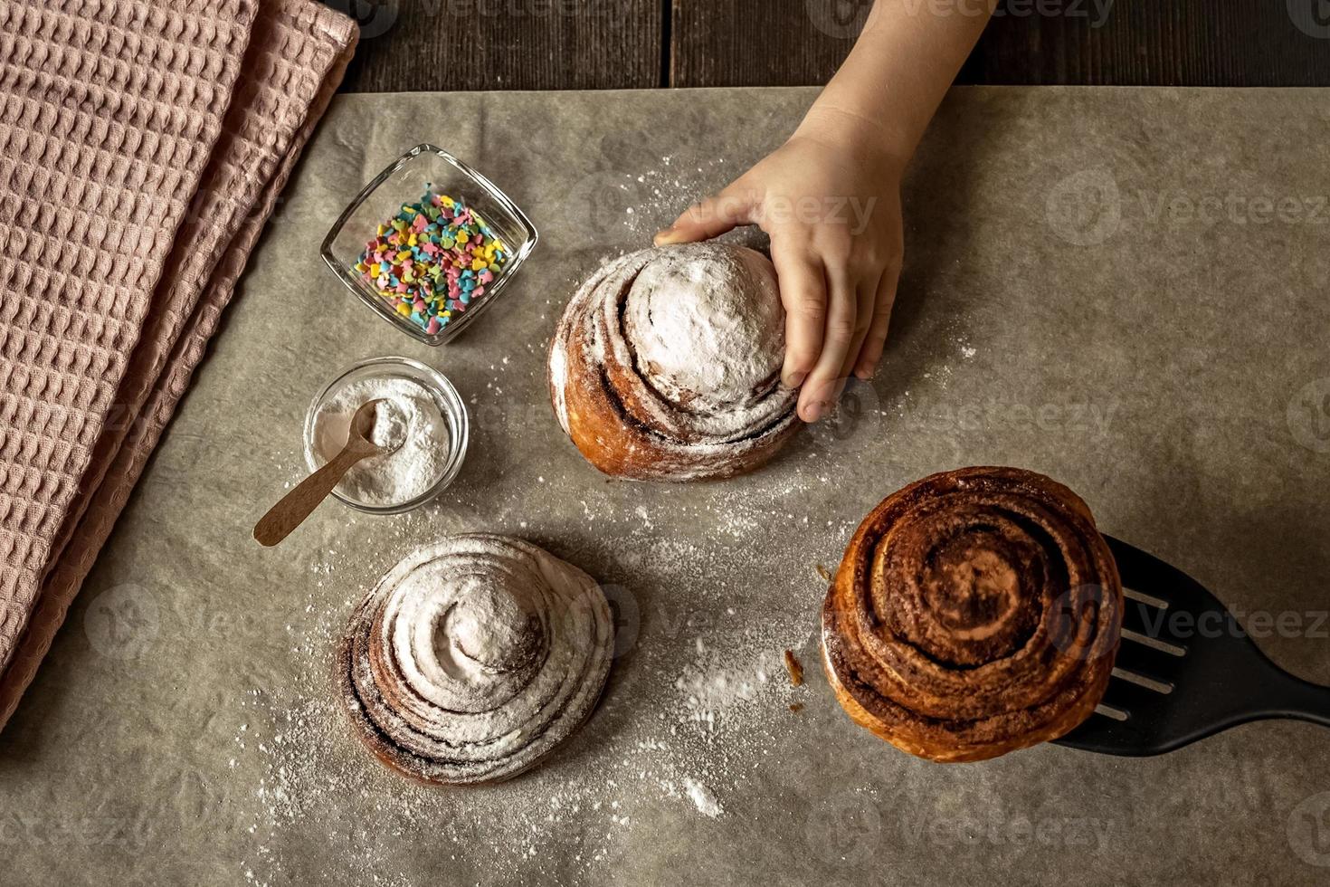 Kinderhand nimmt ein frisch gebackenes Zimtbrötchen foto