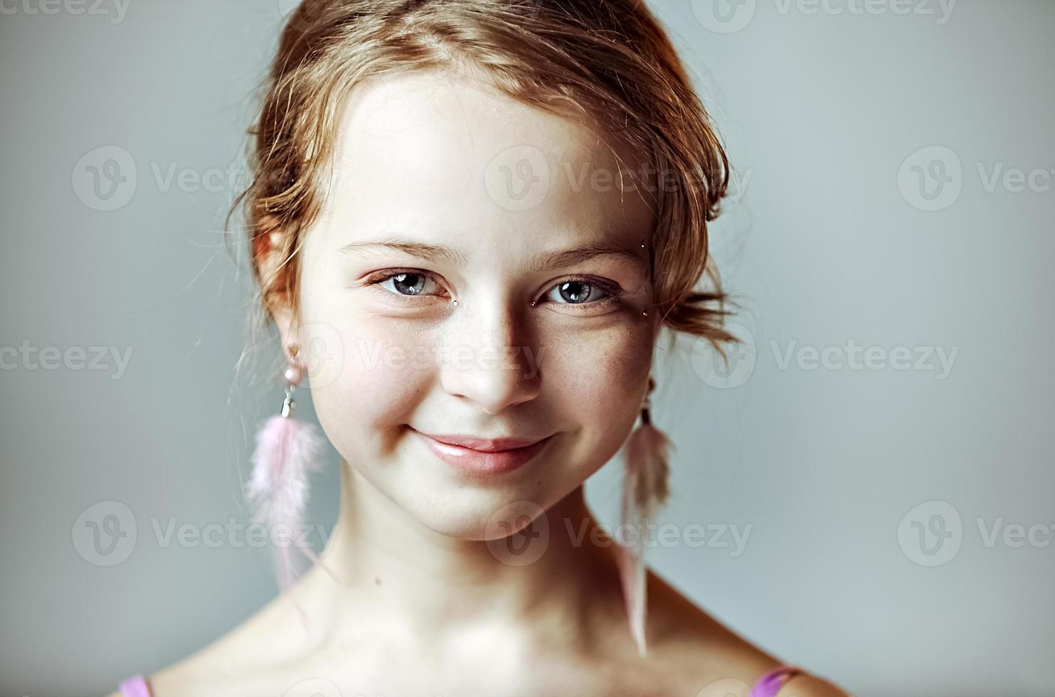 Nahaufnahmeporträt eines jungen Mädchens mit festlichem Make-up für eine Party. Valentinstag. Ohrringe-Federn in den Ohren des Models foto