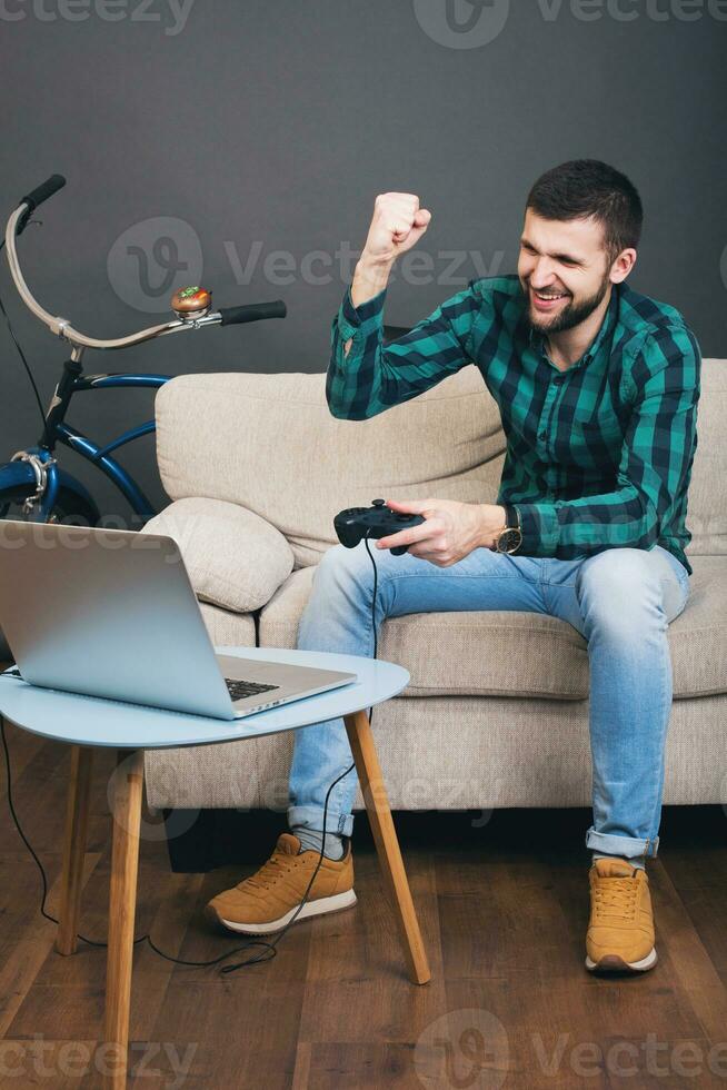 jung Hipster gut aussehend bärtig Mann Sitzung auf Couch beim heim, spielen Video Spiel foto