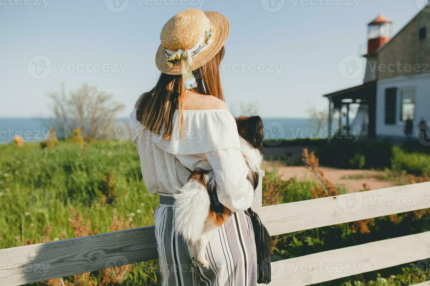 Aussicht von zurück auf stilvoll Frau im Landschaft, halten ein Hund foto