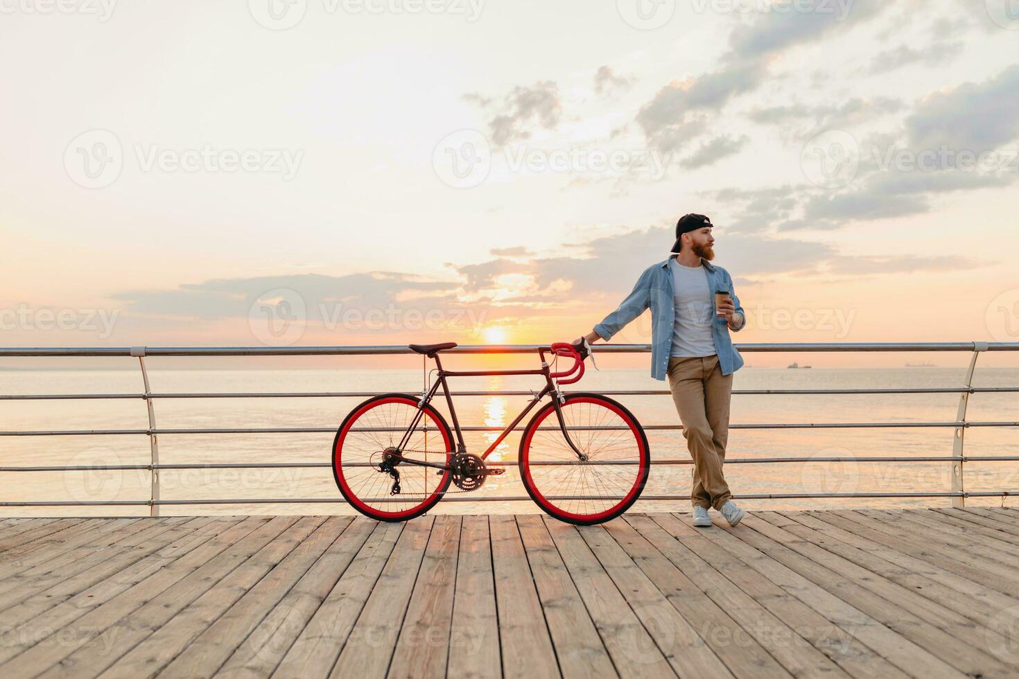 jung bärtig Mann Reisen auf Fahrrad beim Sonnenuntergang Meer foto