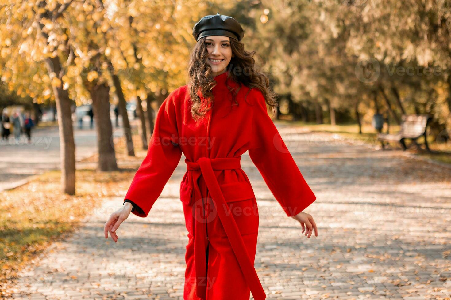 attraktiv stilvoll Frau Gehen im Park gekleidet im warm rot Mantel foto