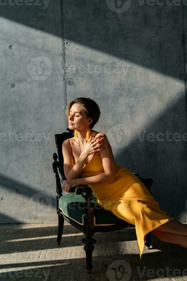 attraktiv Frau im Gelb Sommer- Kleid im Innere Zimmer Beton Mauer Hintergrund foto