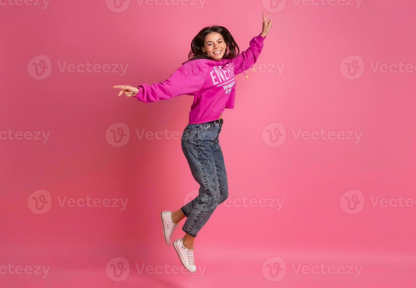 spanisch ziemlich Frau im Rosa Kapuzenpullover lächelnd Springen foto