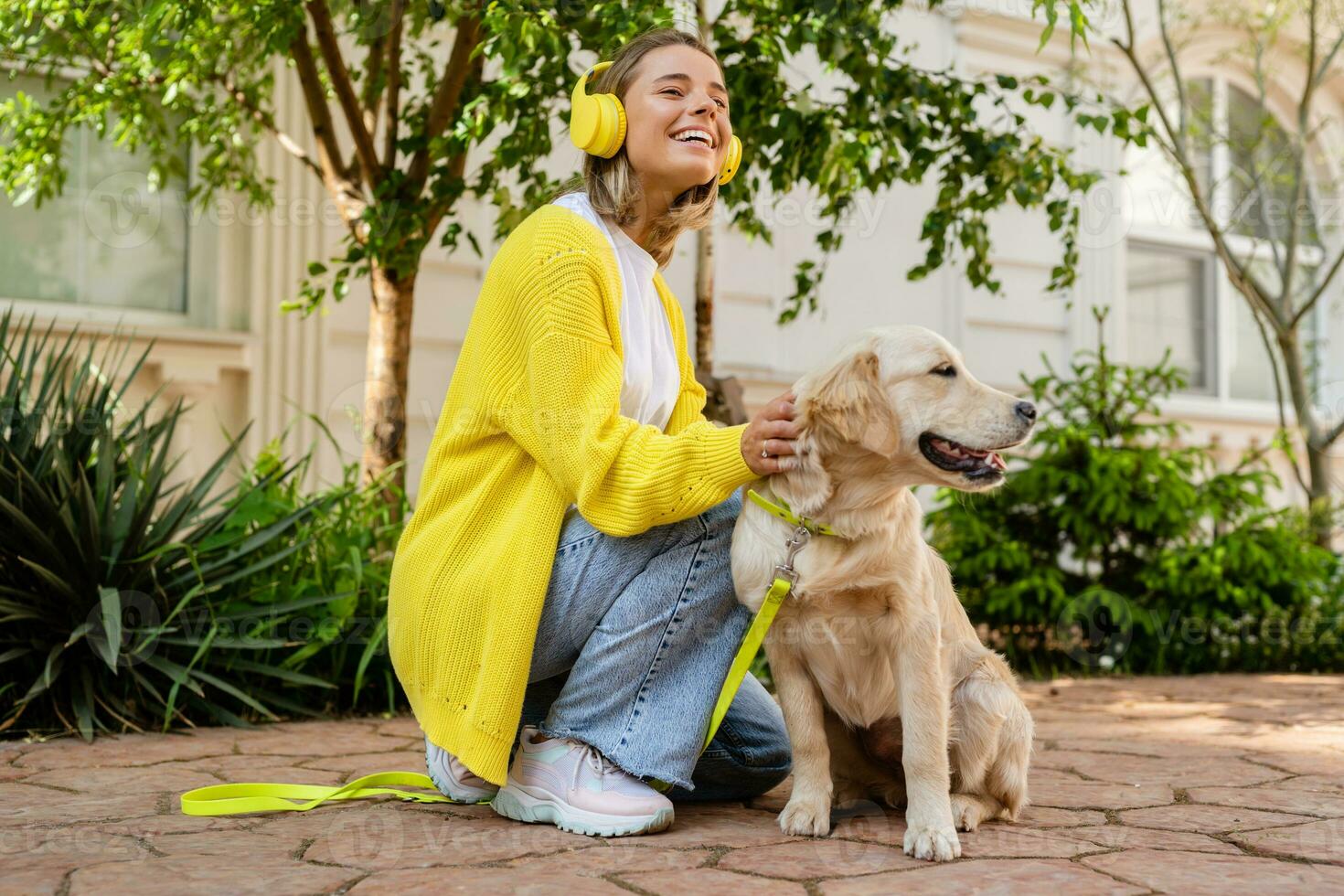 glücklich lächelnd Frau im Gelb Sweatshirt Gehen beim ihr Haus mit ein Hund golden Retriever foto