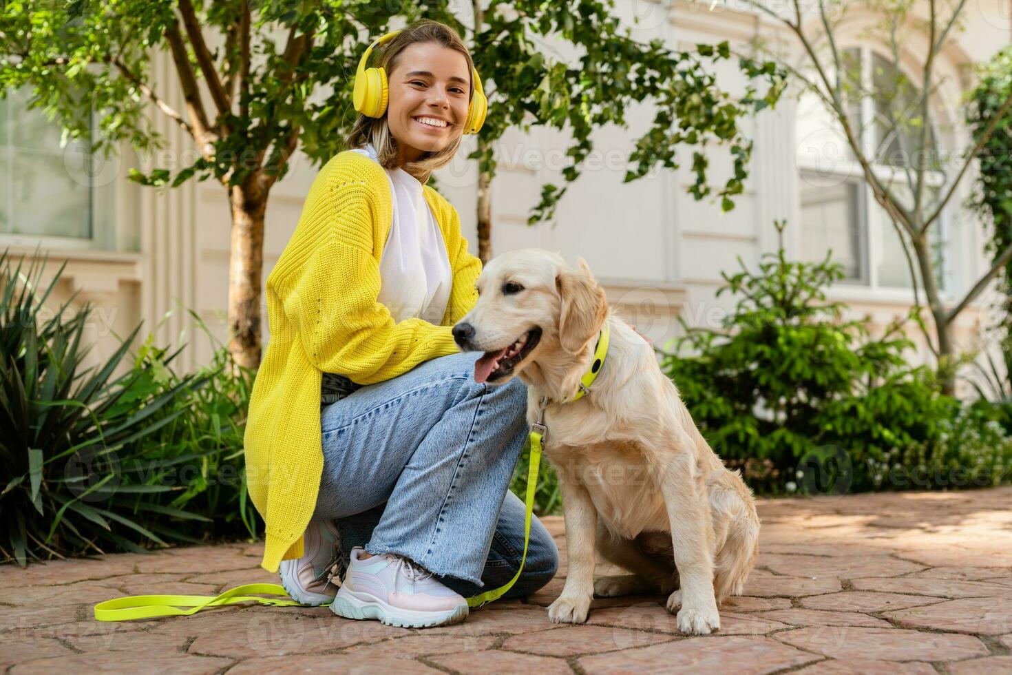 glücklich lächelnd Frau im Gelb Sweatshirt Gehen beim ihr Haus mit ein Hund golden Retriever foto