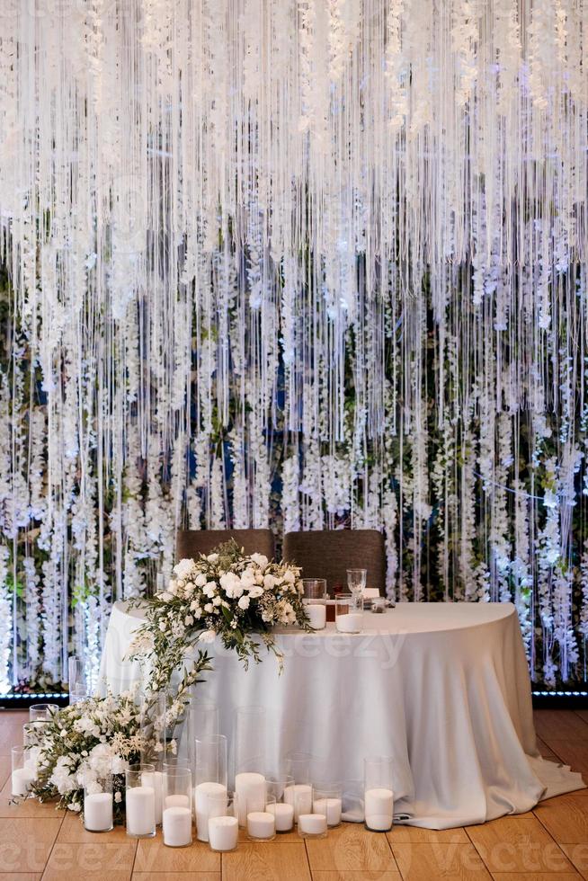 das Präsidium des Brautpaares im Festsaal des Restaurants ist mit Kerzen und Grünpflanzen geschmückt foto