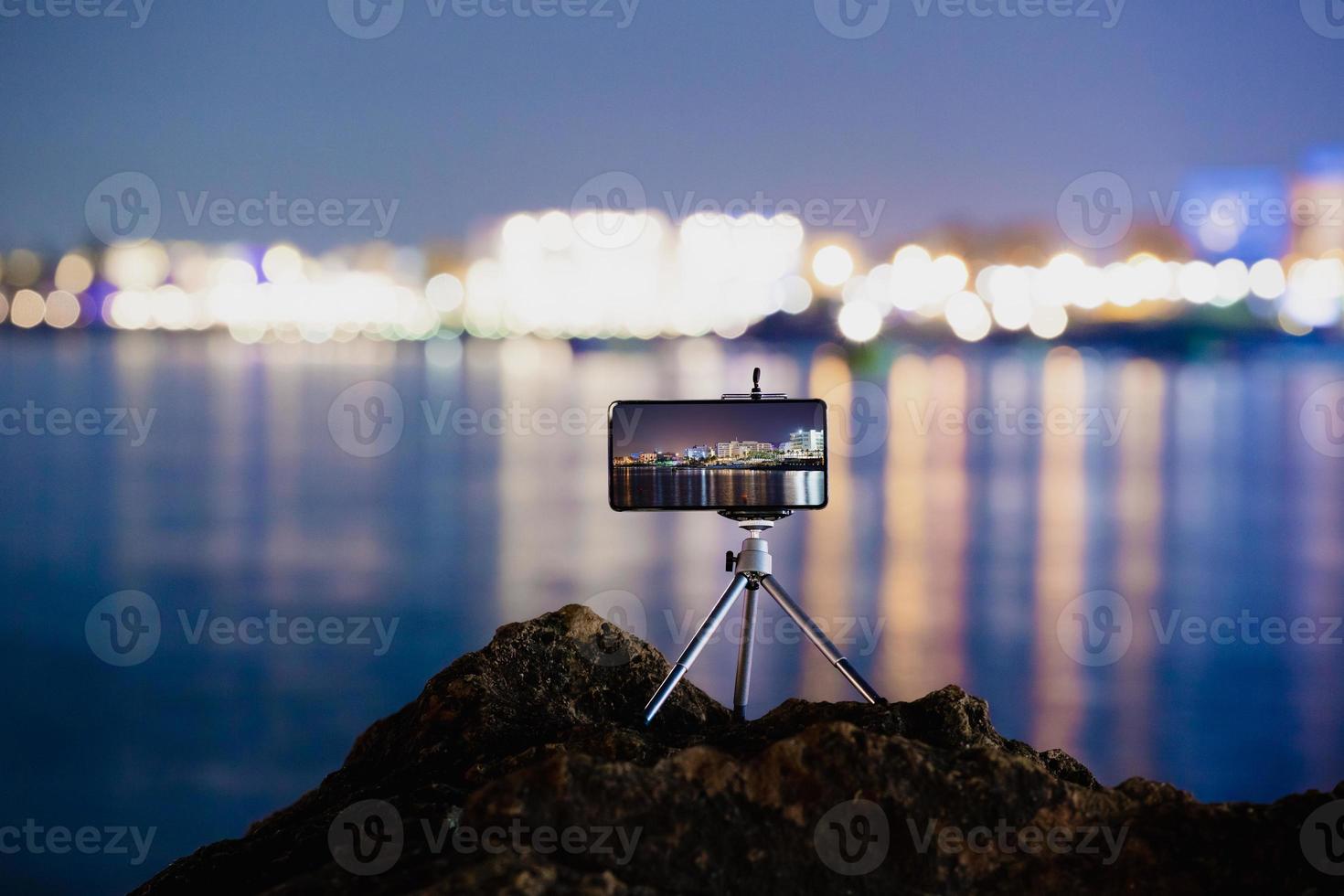 Verwenden eines Smartphones auf einem Stativ mit Langzeitbelichtung des Meeres bei Nacht foto