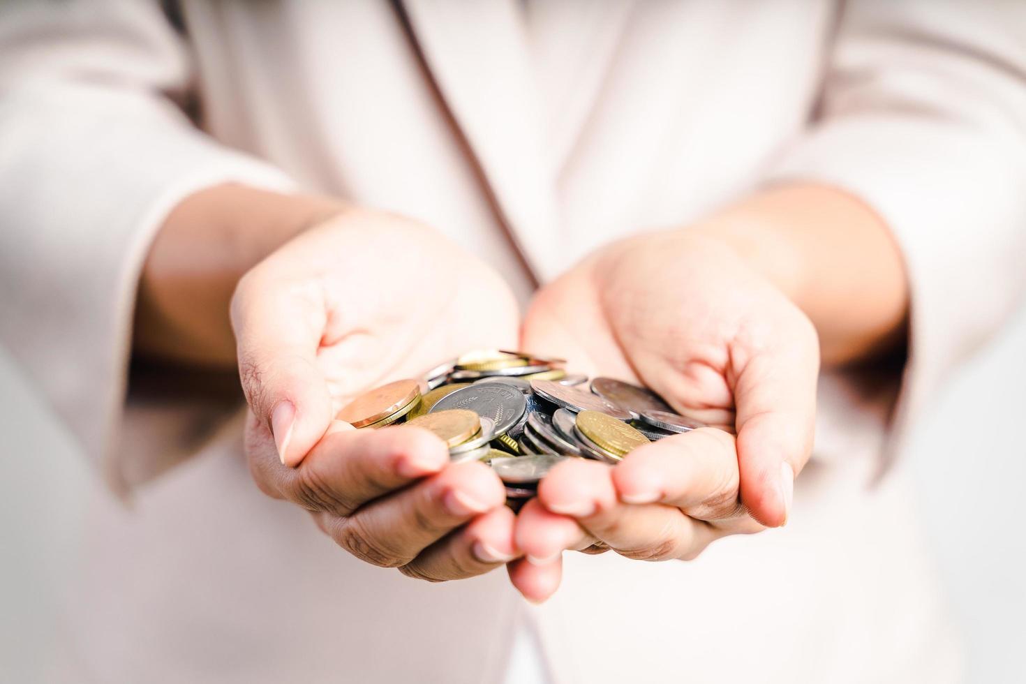 Nahaufnahme von Geschäftsfrauenhänden, die Münzen auf weißem Hintergrund halten. Geld sparen, Finanzkonzept. foto