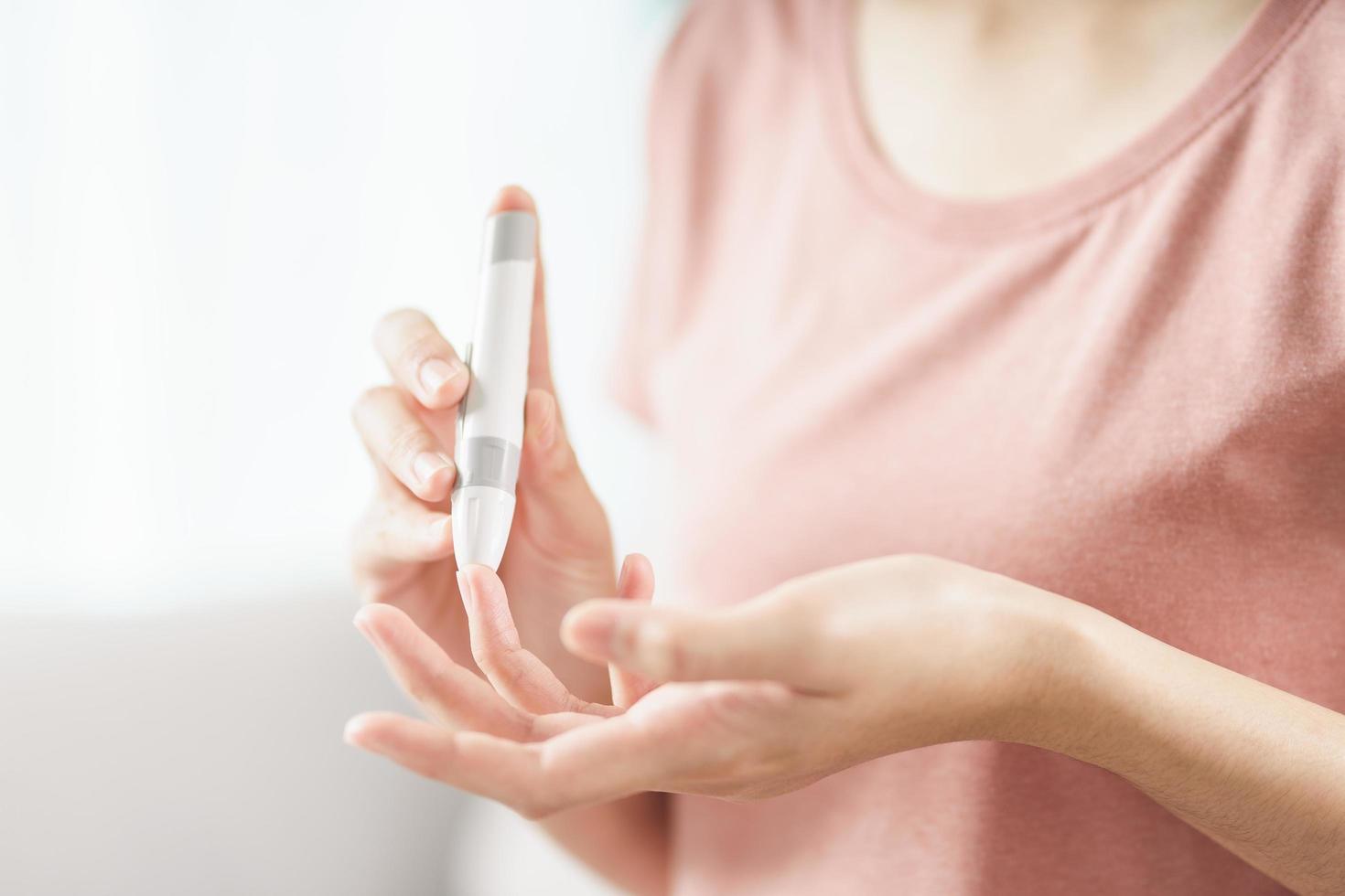 asiatische Frau mit Lanzette am Finger zur Überprüfung des Blutzuckerspiegels durch Glukosemeter, Gesundheitswesen und Medizin, Diabetes, Glykämie-Konzept foto