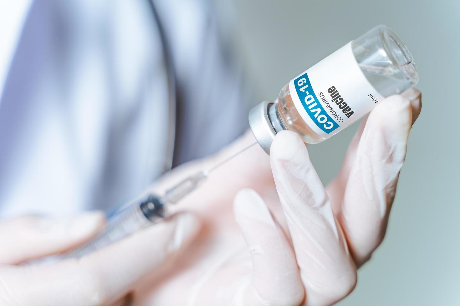 Der Arzt hält eine Spritze mit Covid-19-Impfstoffen in einer Glasflasche. Covid-19-Coronavirus-Behandlungskonzept. foto