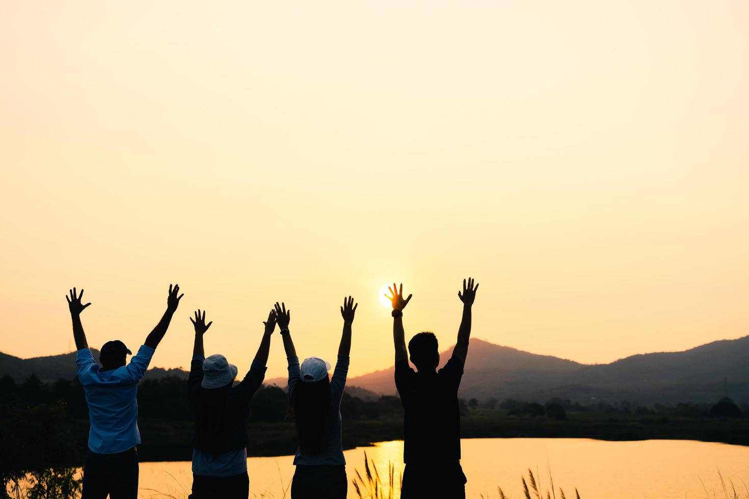 Gruppe von Menschen mit erhobenen Armen, die den Sonnenaufgang auf dem Berghintergrund betrachten. Glück, Erfolg, Freundschaft und Gemeinschaftskonzepte. foto