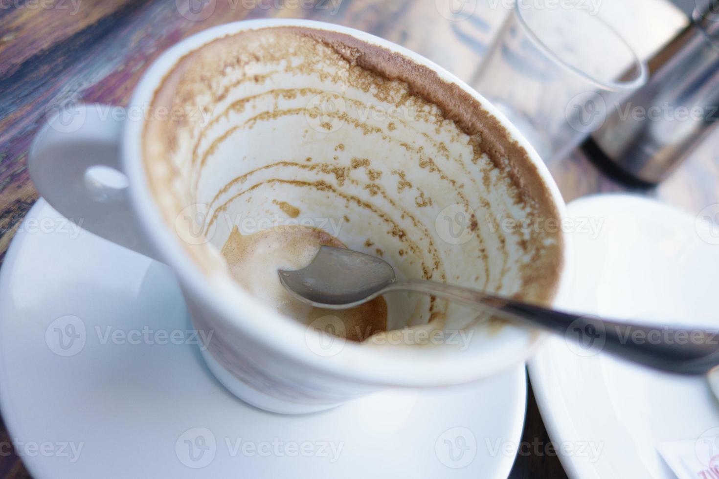 weiße Tasse mit Kaffeeresten auf dem Tisch foto