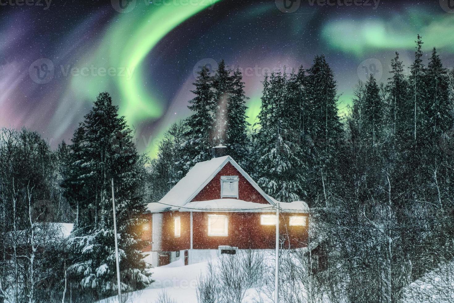 Aurora Borealis über rotem nordischem Haus mit Schnee bedeckt im Winter in der Nacht foto