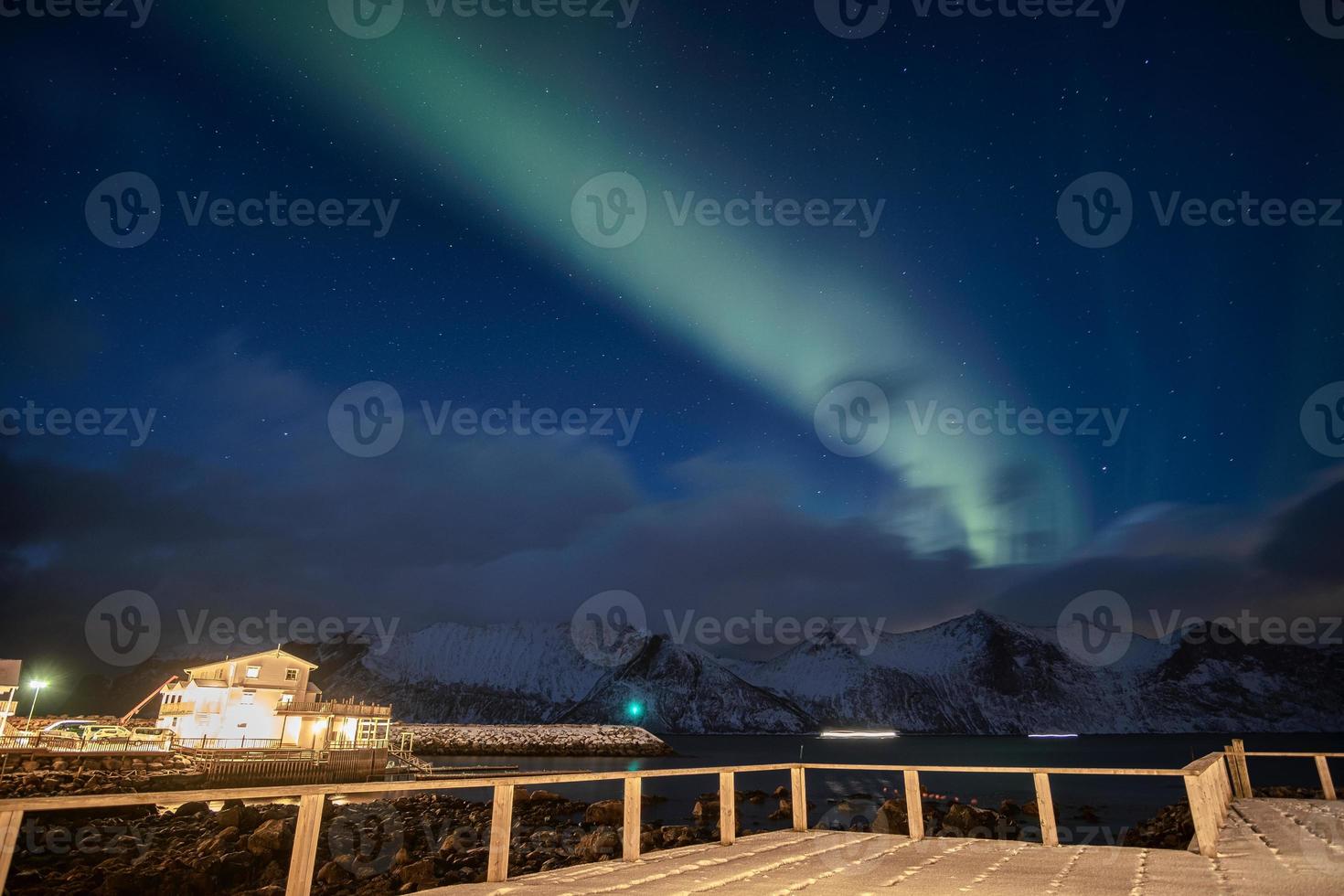 Aurora Borealis oder Nordlicht über schneebedeckten Bergen mit Hausbeleuchtung am Mefjord Brygge foto