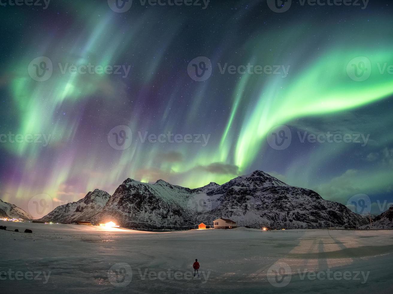 fantastische Aurora Borealis über schneebedeckten Bergen mit Mann stehend foto