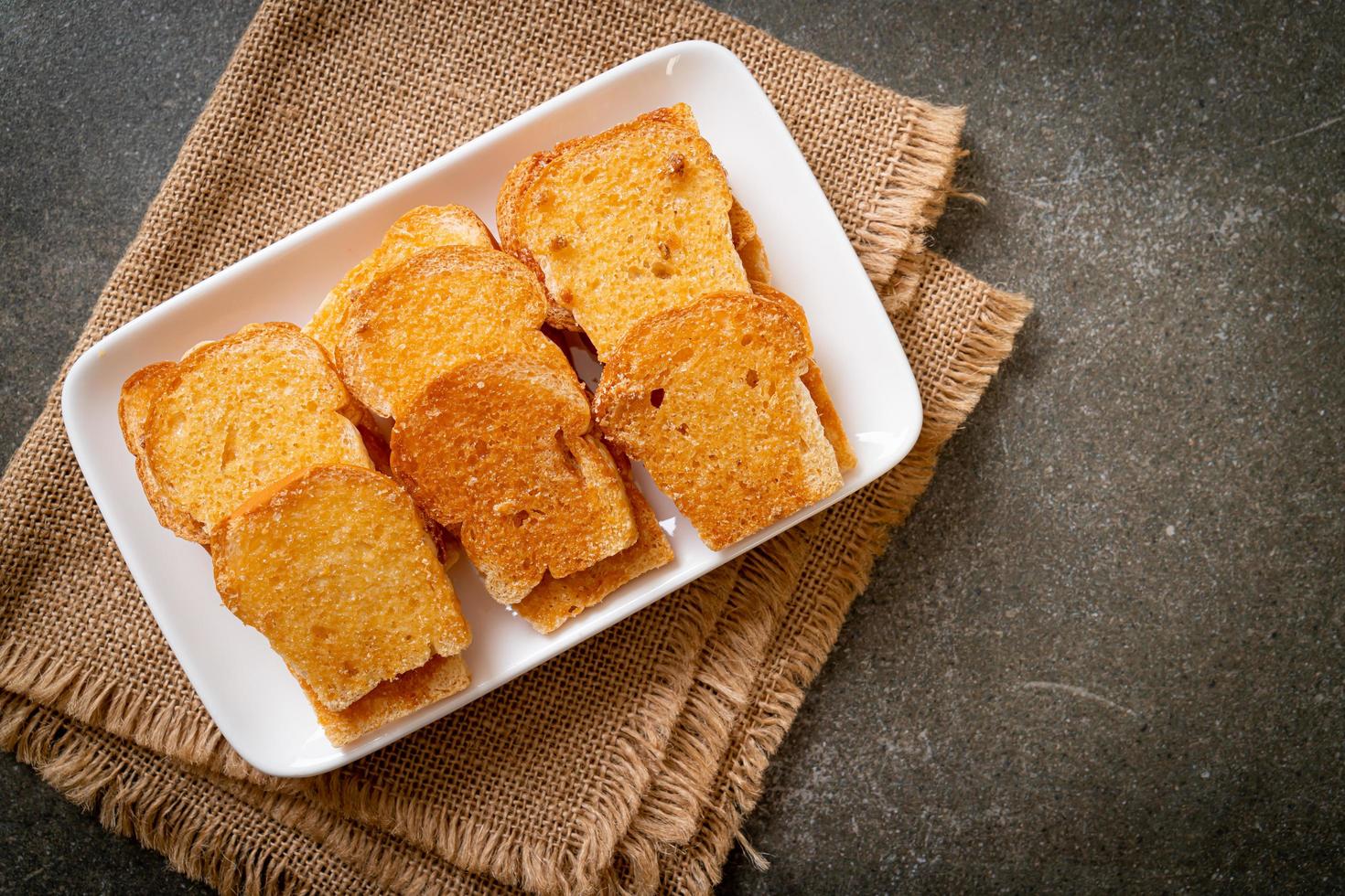 gebackenes knuspriges Brot mit Butter und Zucker auf Teller foto