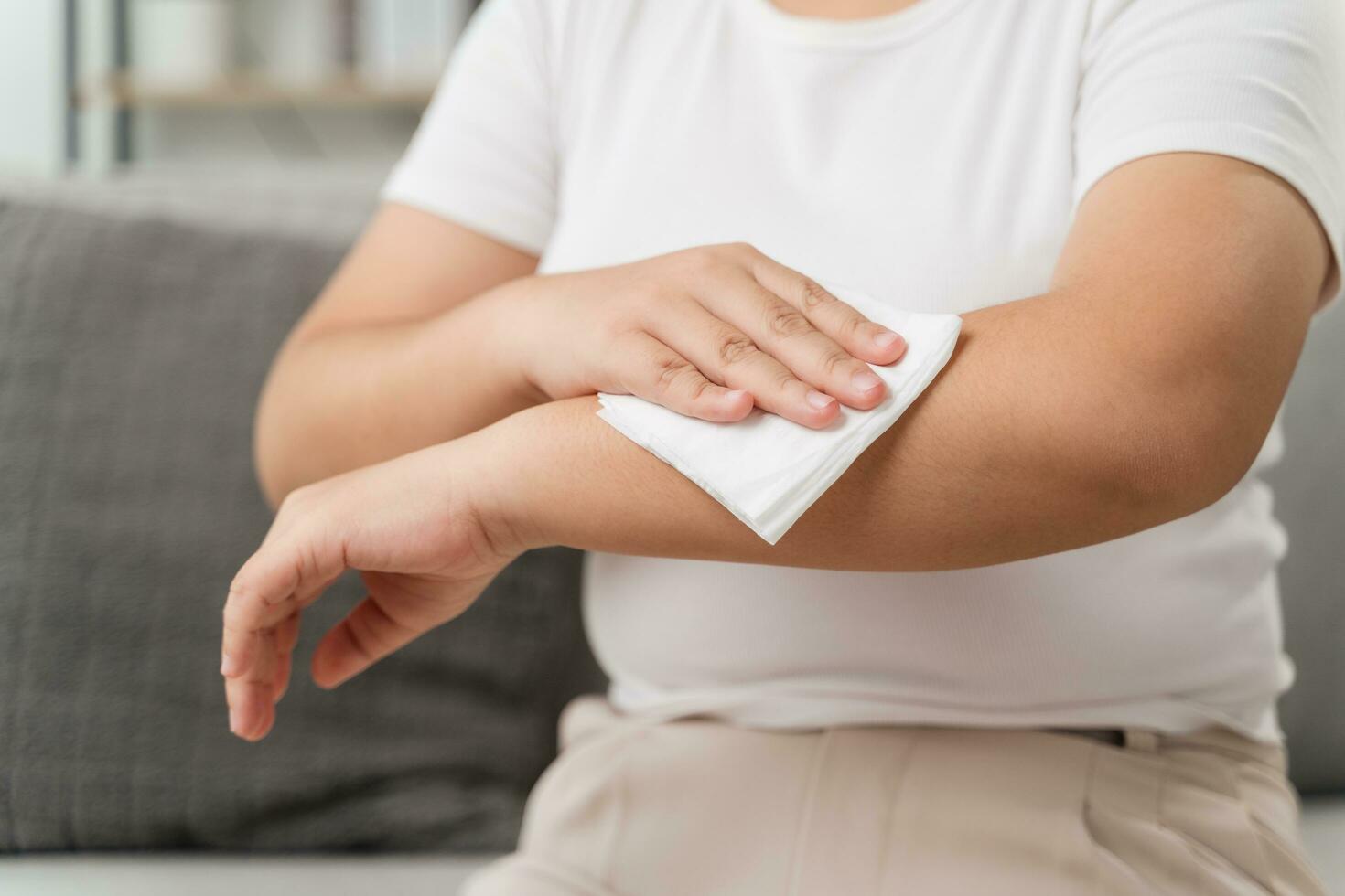 Frau Tücher Reinigung ihr Arm mit ein Gewebe Papier Handtuch. Gesundheitswesen und medizinisch Konzept. foto