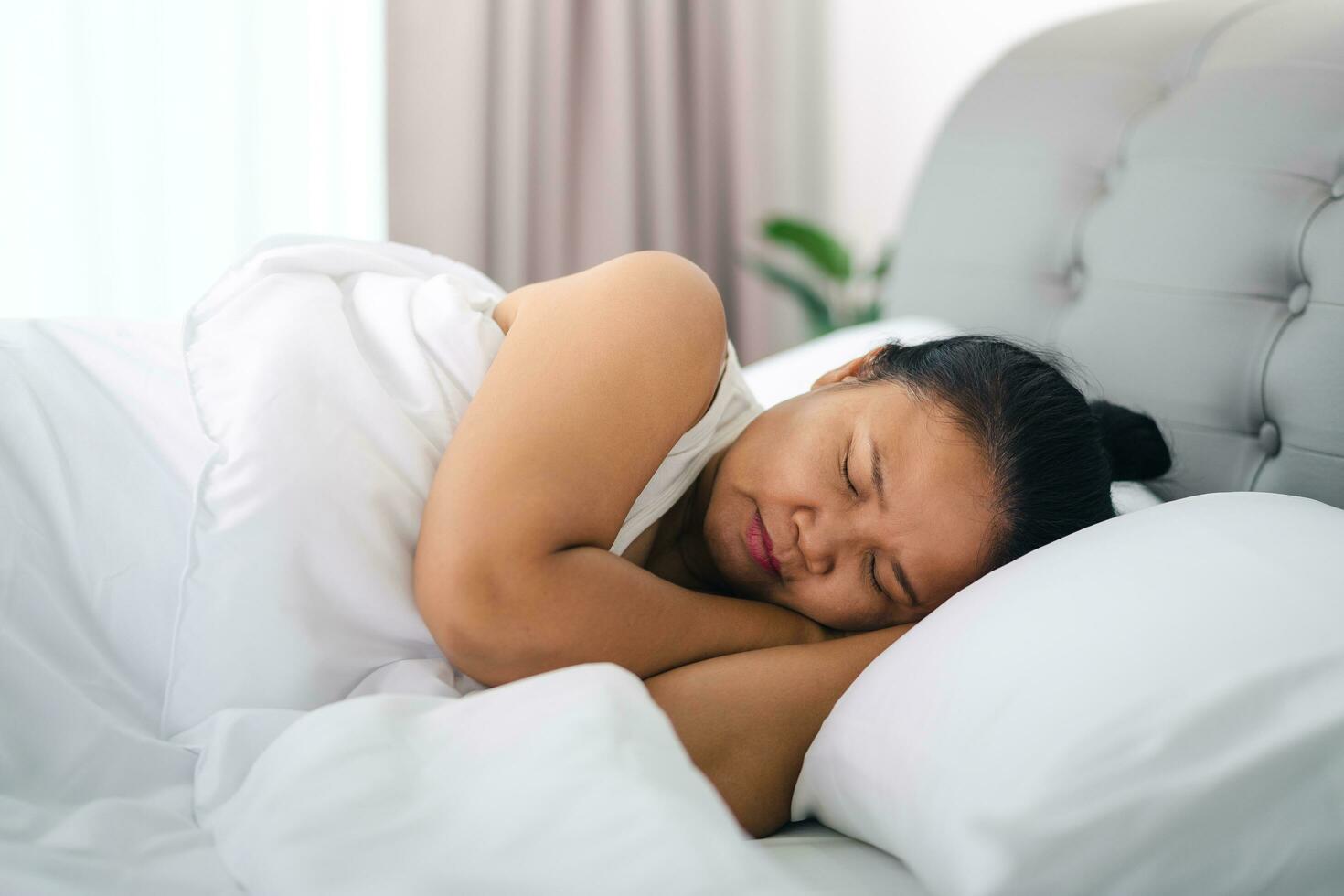 reifen Frau Schlafen auf das Weiß Bett beim heim. foto