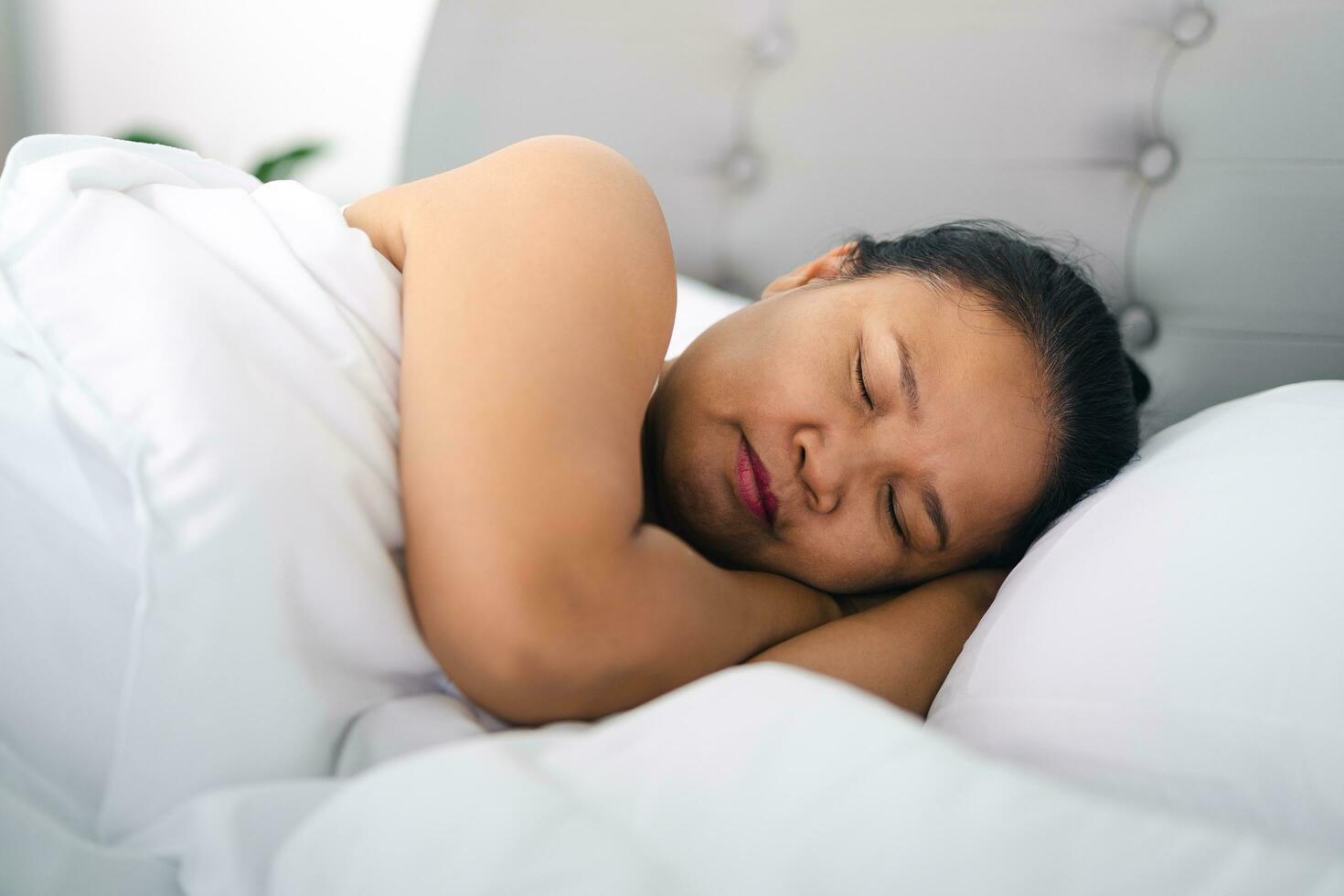 reifen Frau Schlafen auf das Weiß Bett beim heim. foto