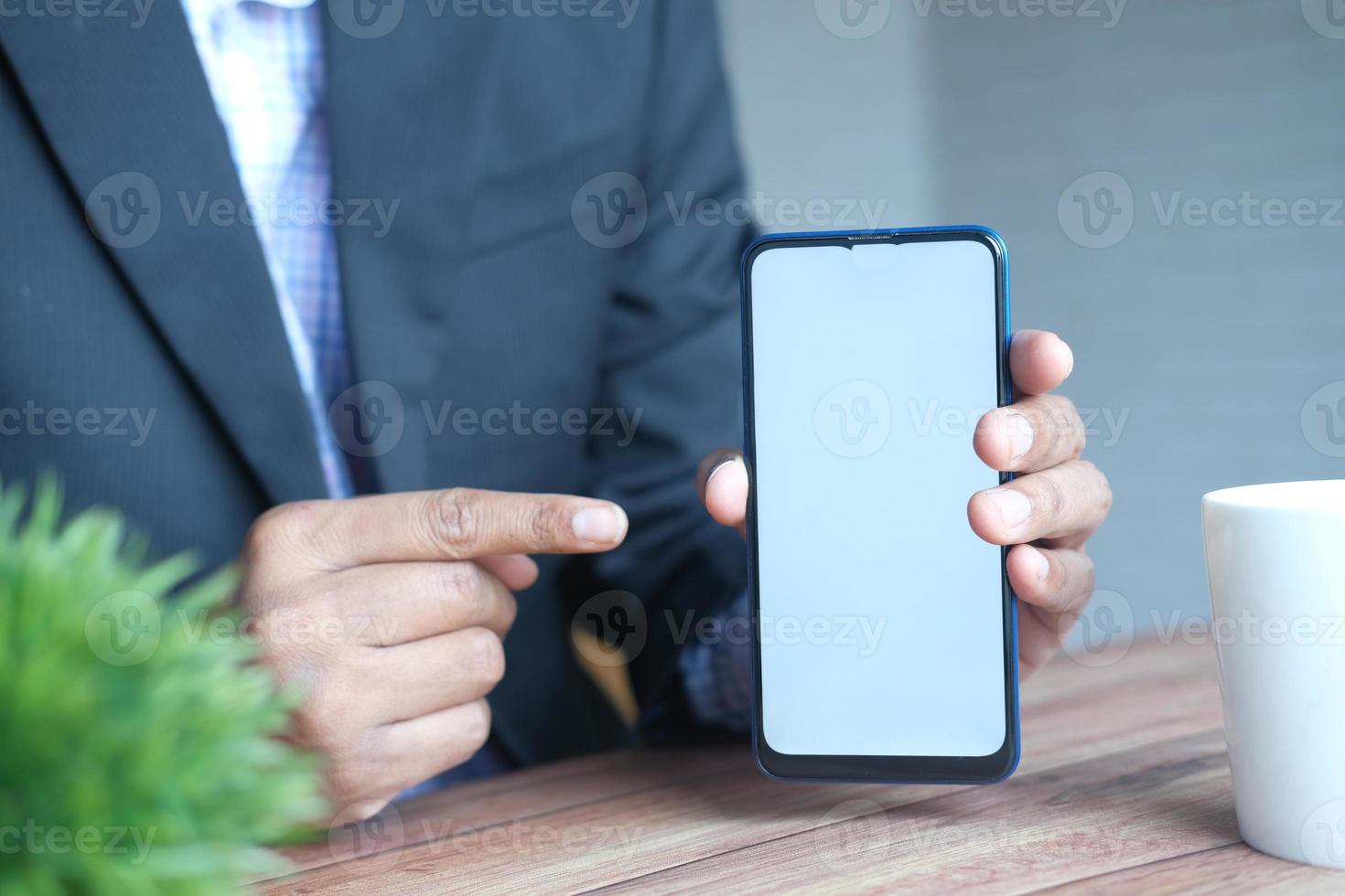 Nahaufnahme der Hand des jungen Mannes mit Smartphone mit grünem Bildschirm foto