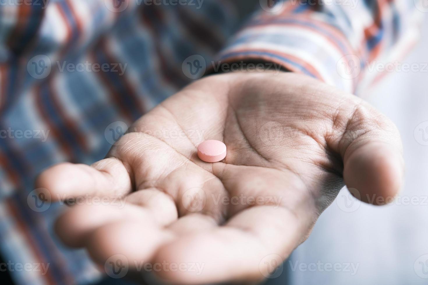 Nahaufnahme der Hand des Mannes, die eine medizinische Pille hält foto