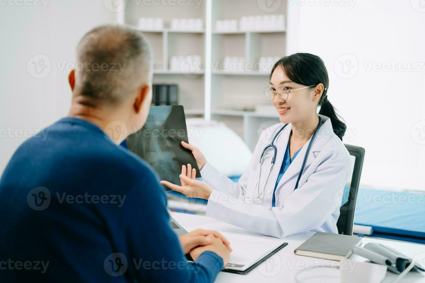 ernst Asien weiblich Arzt mit Zwischenablage ist liefern großartig Nachrichten sich unterhalten diskutieren Ergebnisse oder Symptome mit weiblich geduldig im Klinik oder Krankenhaus foto