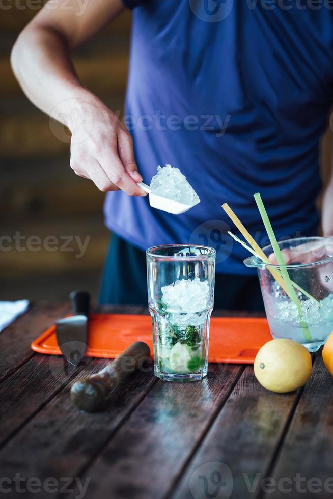 Barmann bereitet Fruchtalkoholcocktail auf Basis von Limette, Minze, Orange, Limonade zu foto