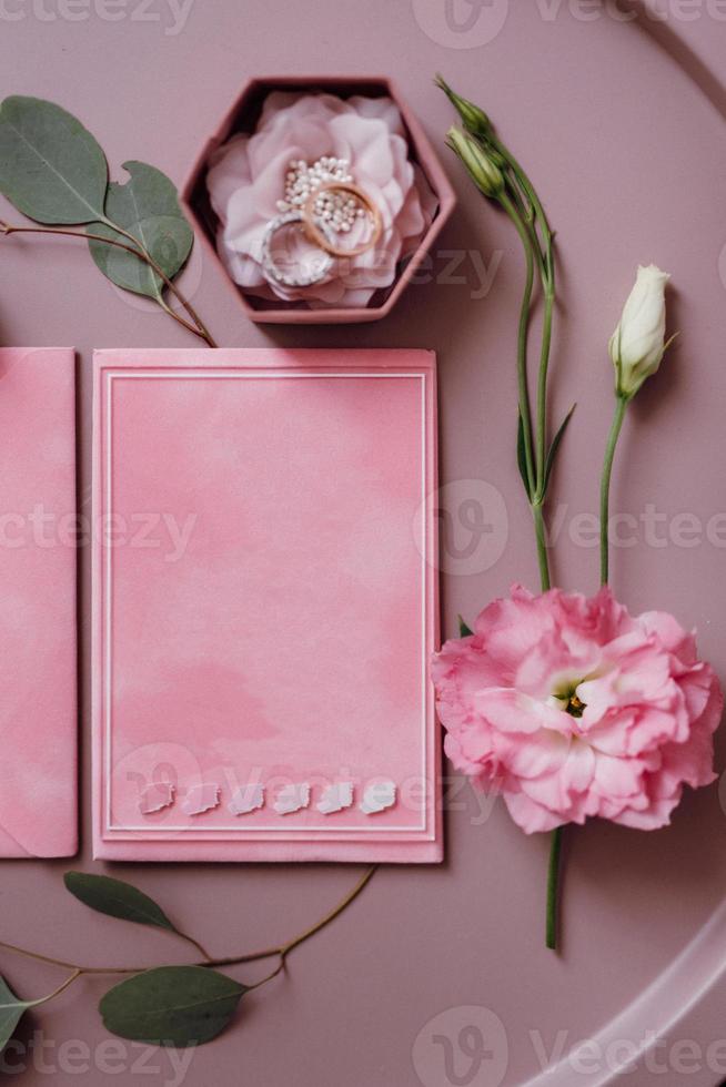 Hochzeitseinladung in einem grauen Umschlag auf einem Tisch mit grünen Zweigen foto