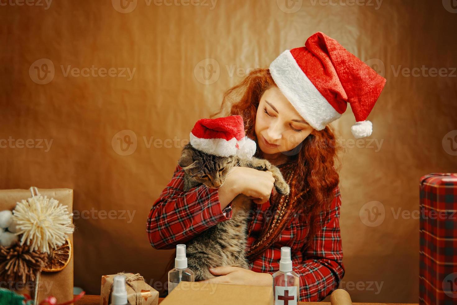 Frau in Nikolausmütze mit Katze in Weihnachtsmütze. foto