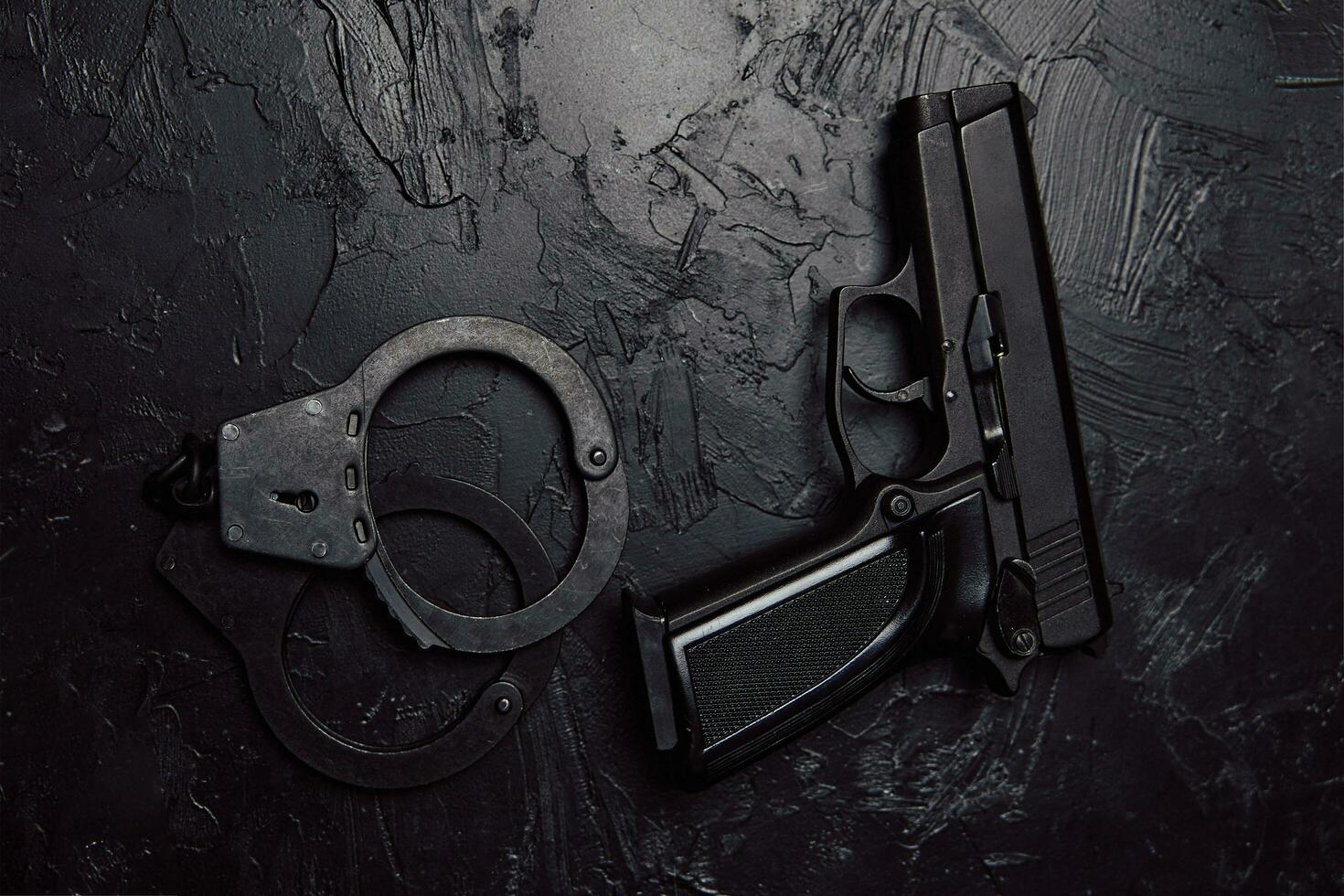 Pistole und Handschellen auf schwarzem strukturiertem Tisch. foto