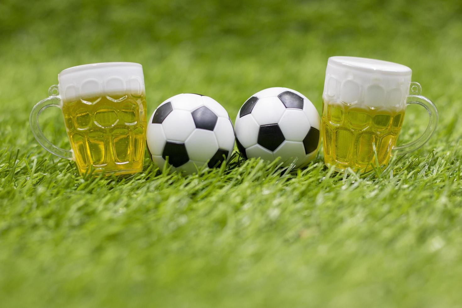 Fußball und ein Glas Bier stehen auf grünem Gras foto