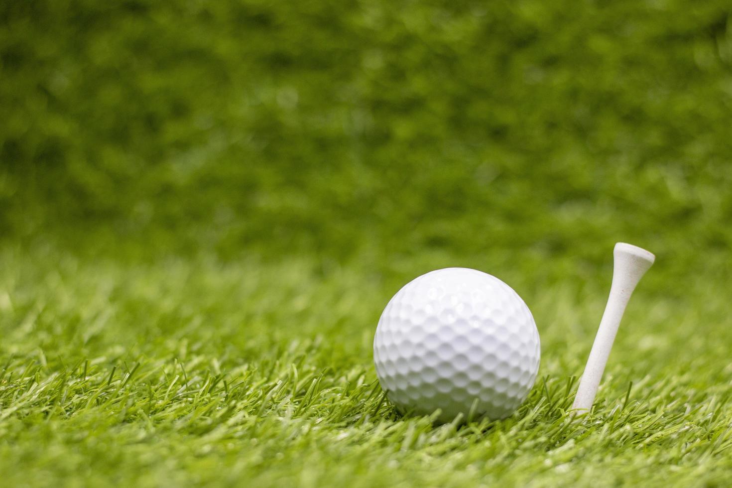Golfball mit Tee sind auf grünem Gras foto