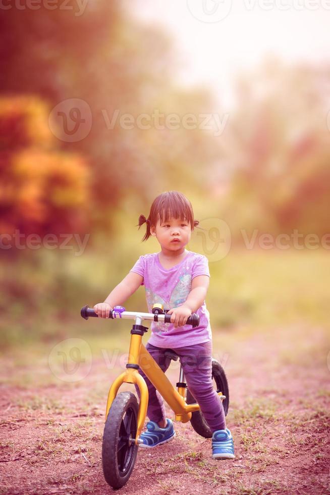 kleines Mädchen, das Laufrad im Park reitet foto