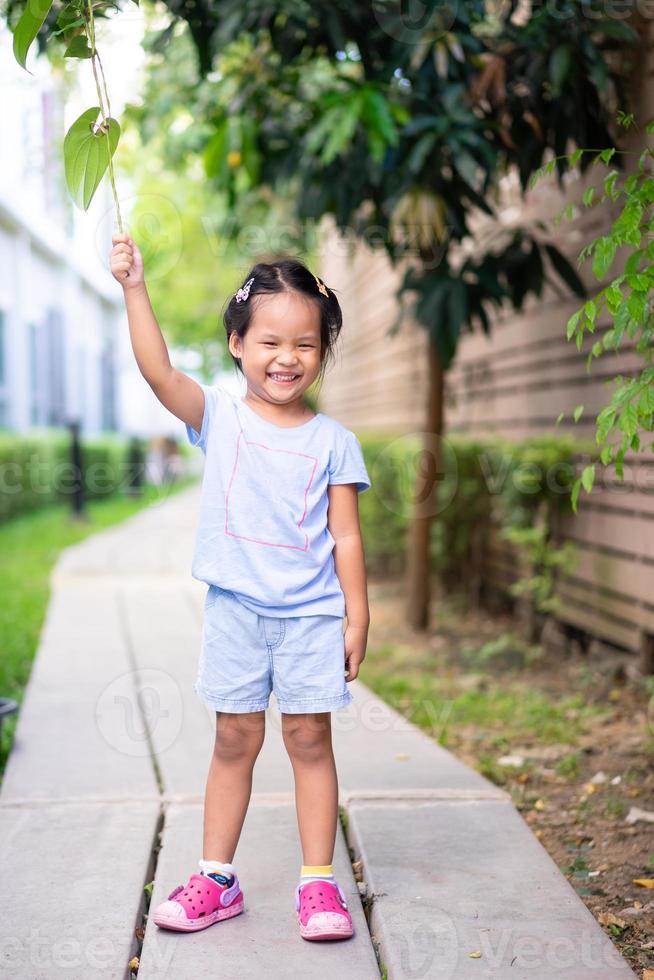 glückliches kleines Mädchen, das auf Fußweg im Park steht foto