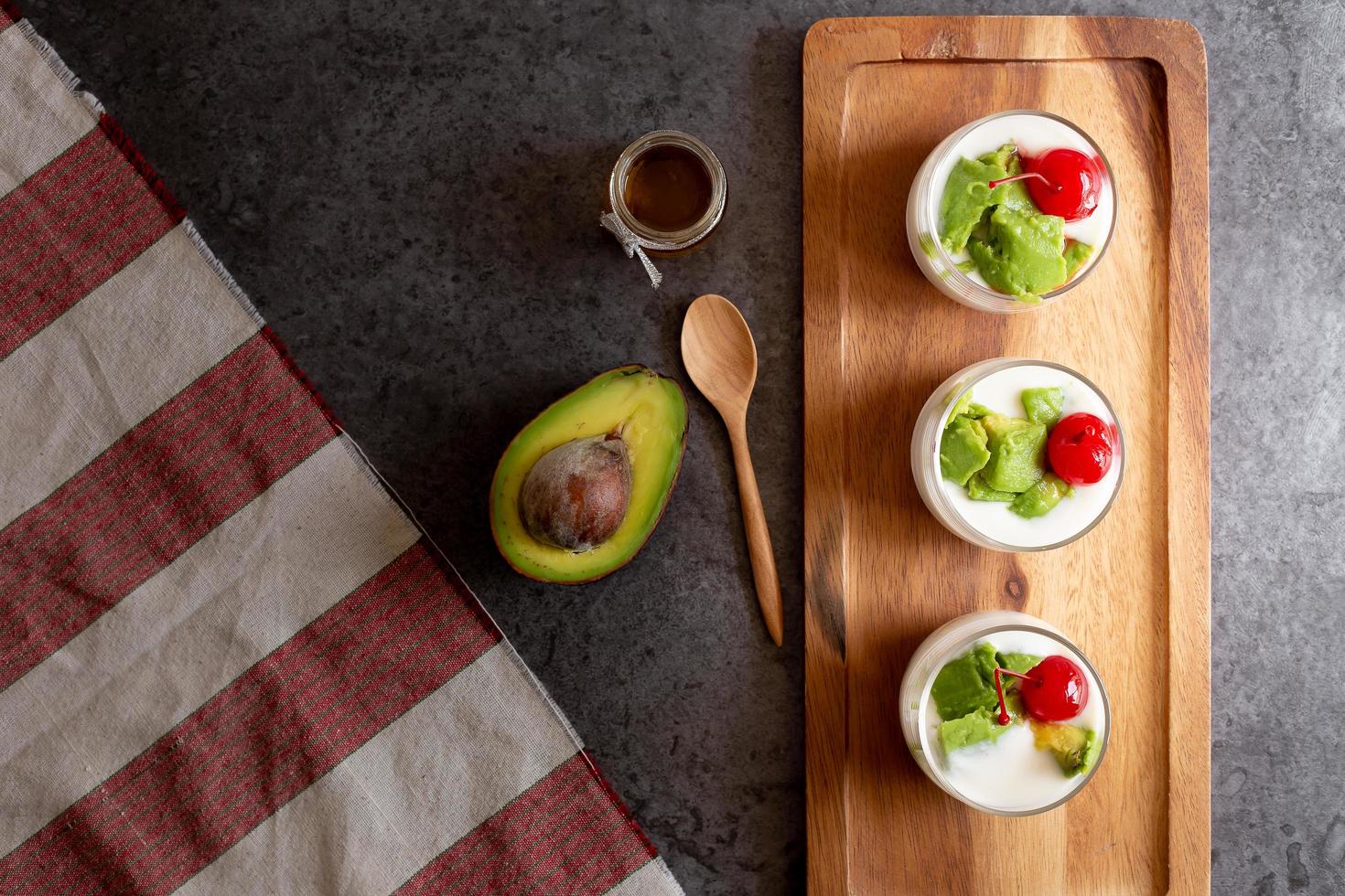 Glas Kirsche und Avocado in Joghurt auf Holzuntergrund geschnitten foto