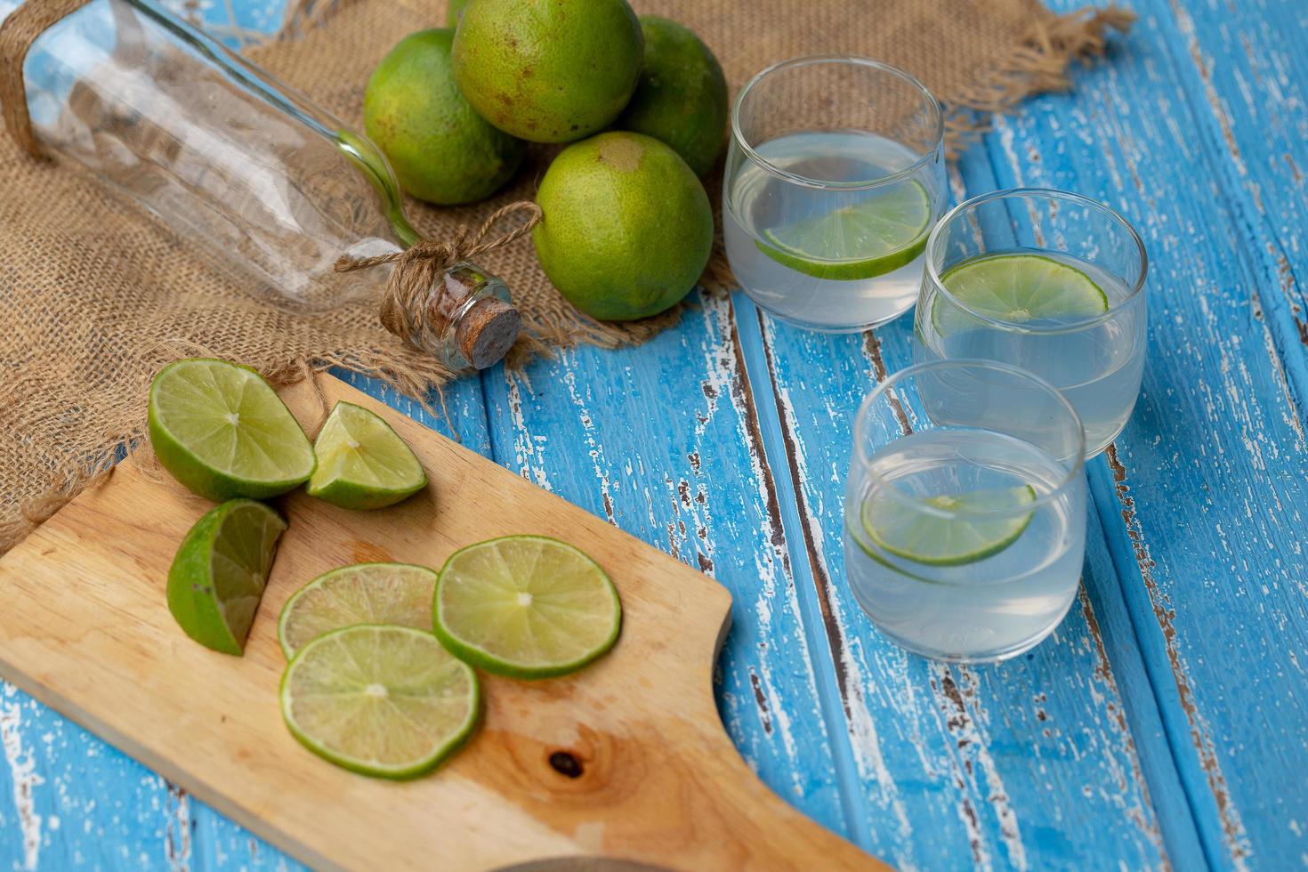 Limettensaft und Zitrone auf einem blauen Holztisch foto