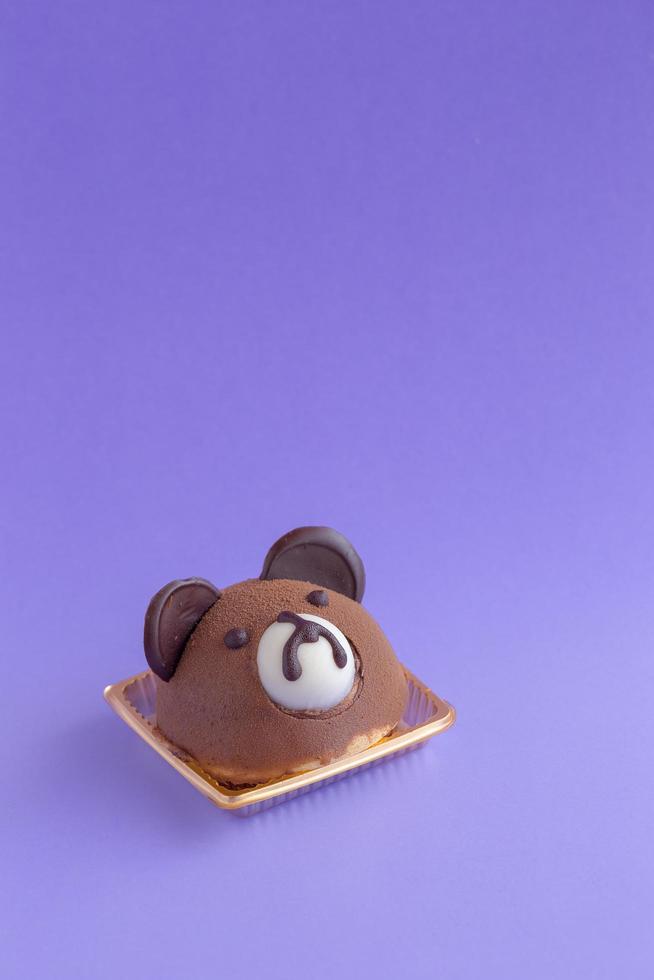 Brauner Teddybärkopf-Schokoladen-Chiffon-Kuchen auf violettem Hintergrund und Kopierraum foto