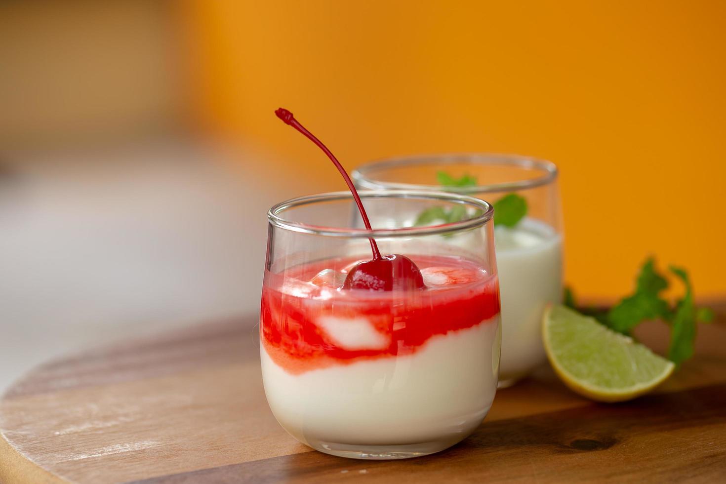 Glas Kirschjoghurt auf einem braunen Holztisch foto