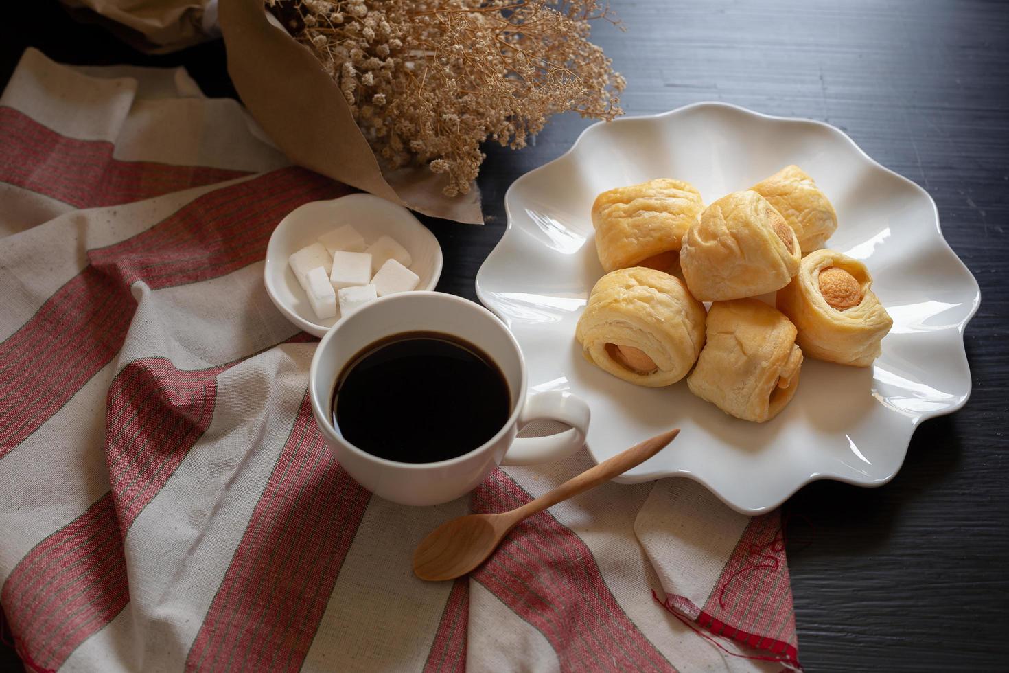 leckere Miniwurst in Brötchen und Tasse heißen Kaffee auf dunklem Hintergrund foto